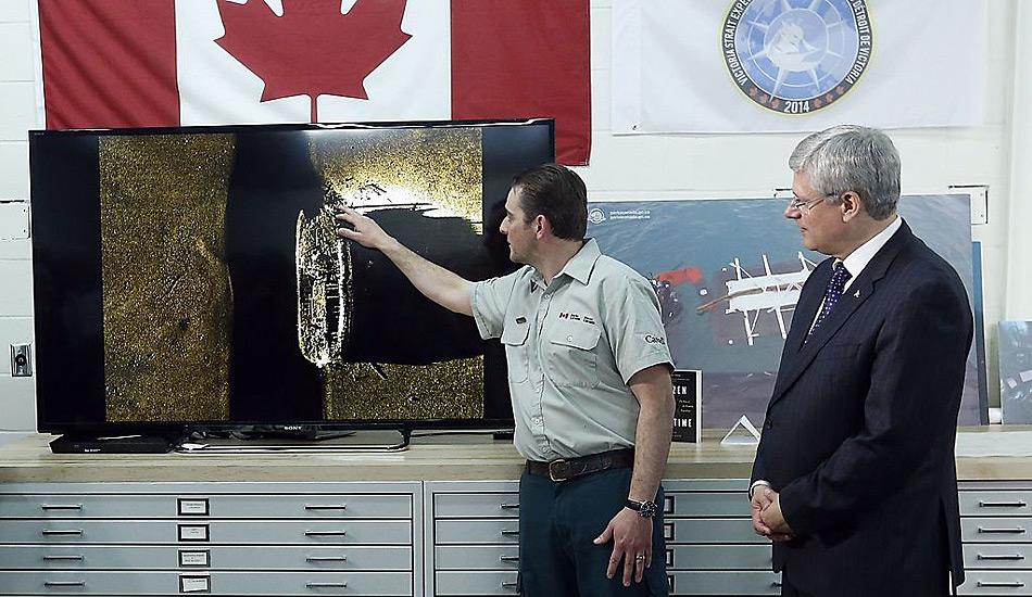 Kanadas Premierminister Stephen Harper beobachtet wie Parkranger Ryan Harris die Entdeckung eines von zwei Schiffen aus der Franklin-Expedition am 9. September in Ottawa erklärt.